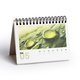 Paper desk calendar with stand and spiral binding.